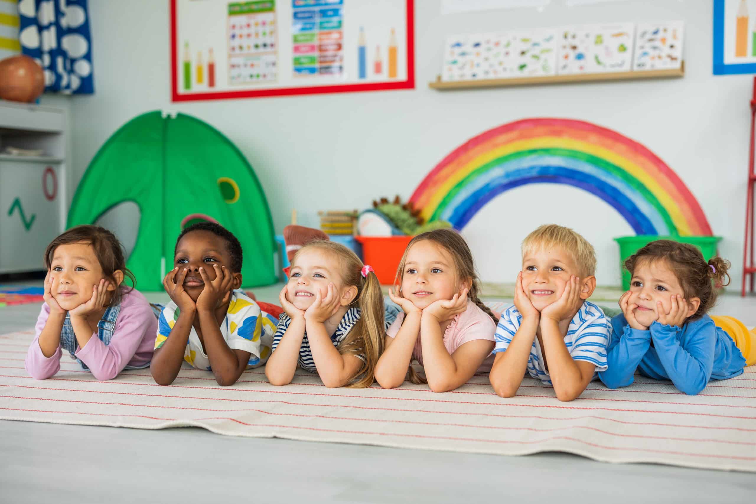Happy children are sitting on the floor in the kindergarten