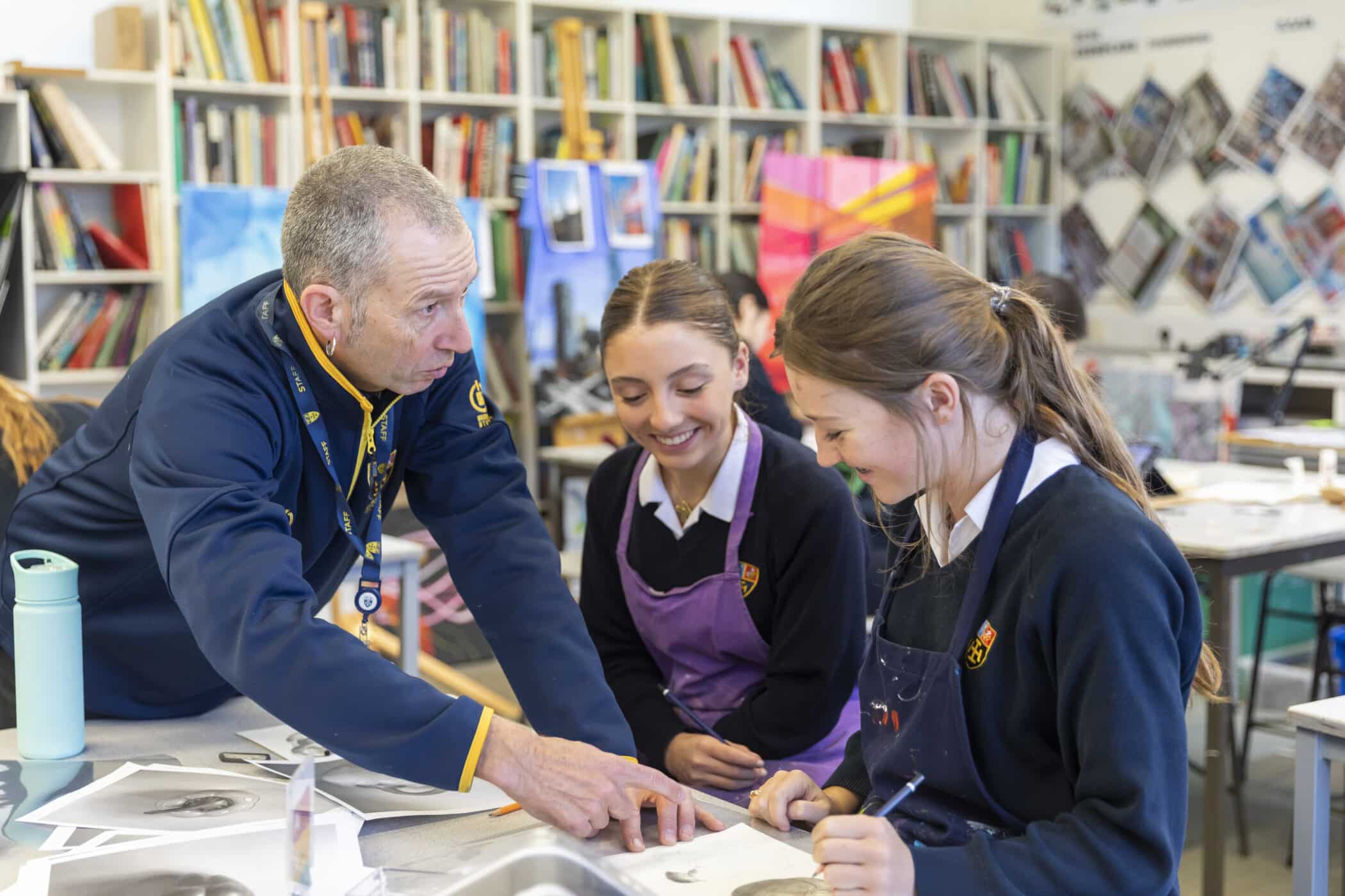 Male art teacher helps pupils with their work